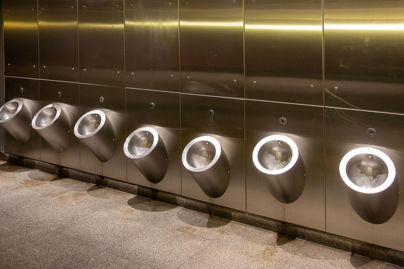 Row of modern illuminated urinals in a clean, upscale restroom facility